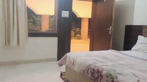 Une chambre à coucher avec un lit, une fenêtre et une porte donnant sur un balcon.