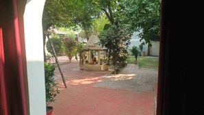 Une cour avec un kiosque, des plantes en pot et un chemin pavé de briques.