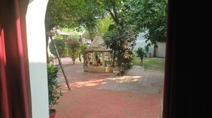 A courtyard with a gazebo, potted plants, and a brick pathway. - Mridul Homestay Orchha  (Orchha)