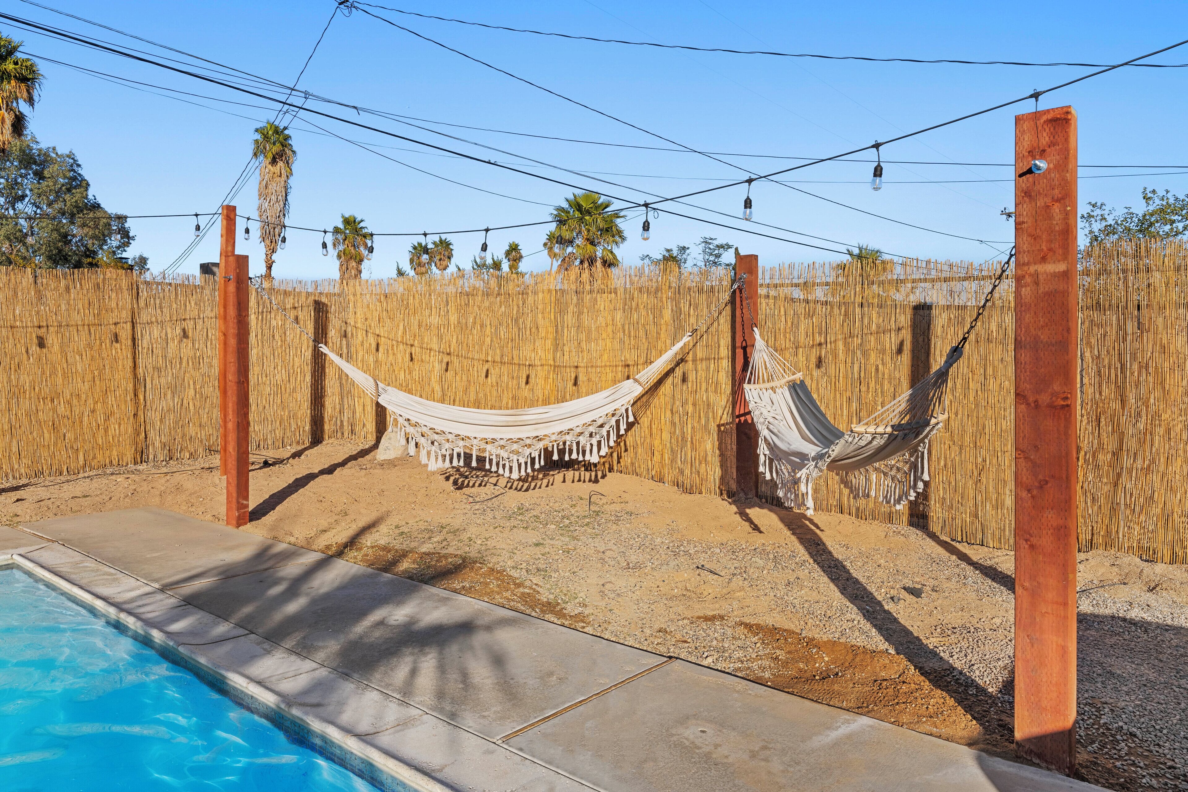 Zona de piscina amb dues cadiretes i una tanca de bambú.