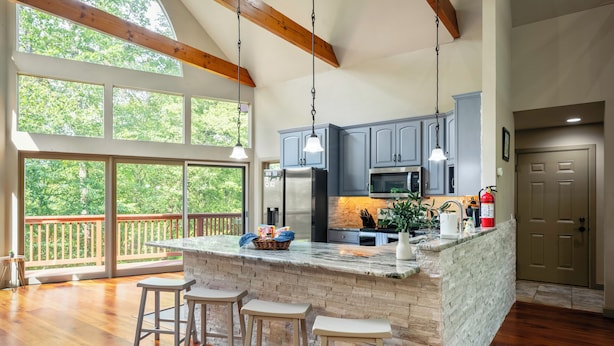 A spacious kitchen with a large island, bar stools, and a view of the outdoors.