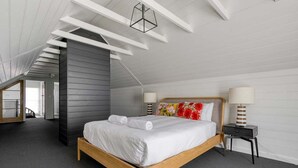 A modern bedroom with a wooden bed, grey walls, and a sloped ceiling. - Talina - History in the Heart of St Helens (Break O'Day)