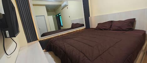 Habitación de hotel con una cama grande, un televisor de pantalla plana en la pared y un espejo que refleja el cuarto.