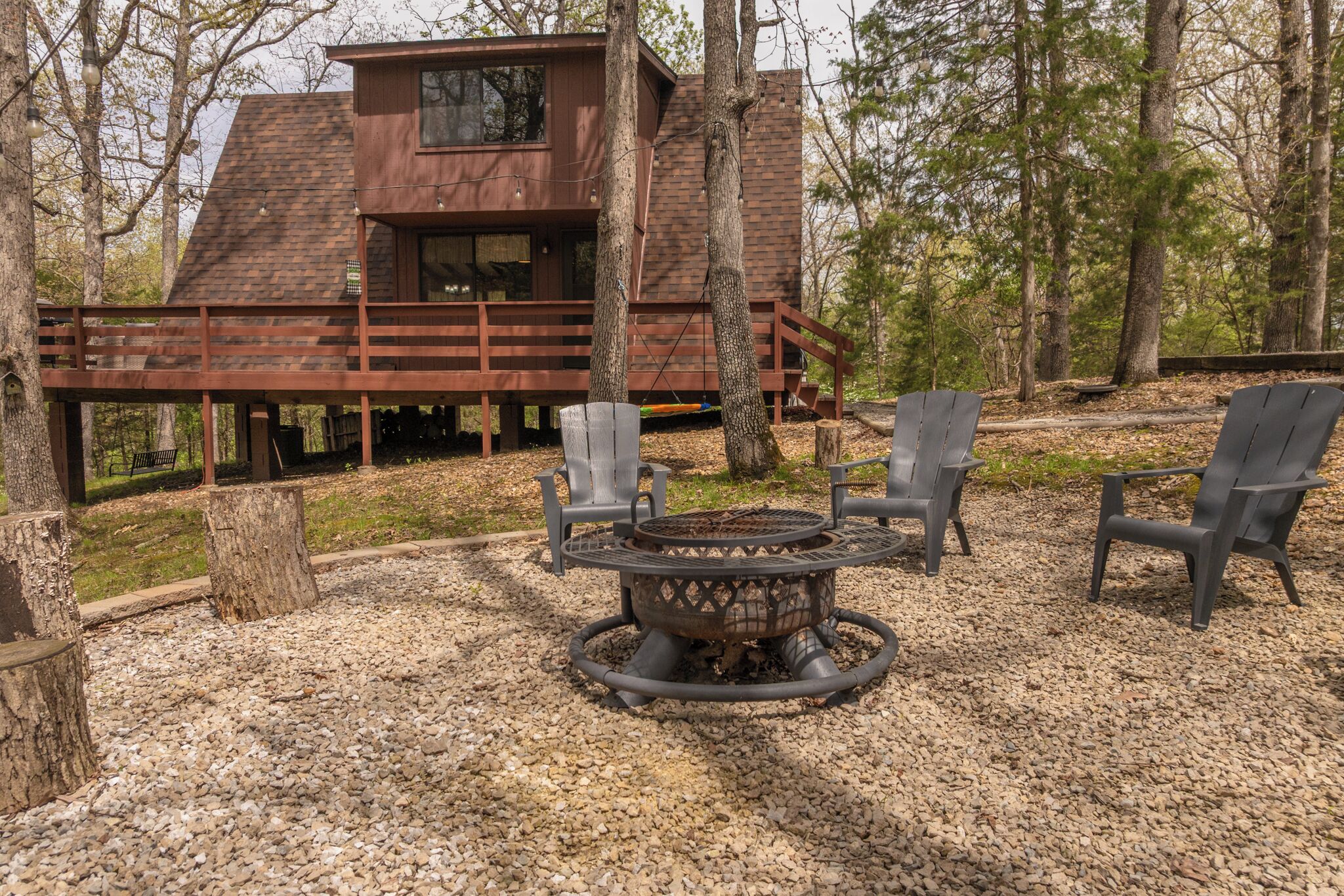 Eine Hütte mit einer Terrasse, einer Feuerstelle und vier Adirondack-Stühlen.