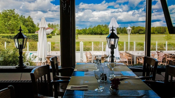An outdoor dining area with tables set for two, chairs, and decorative lanterns.