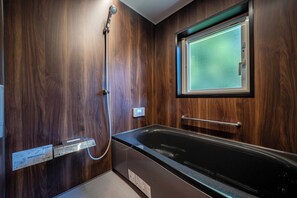 A modern bathroom with a wooden wall, a glass-enclosed shower, and a built-in bathtub. - NISEKO Mt.Village (Niseko)