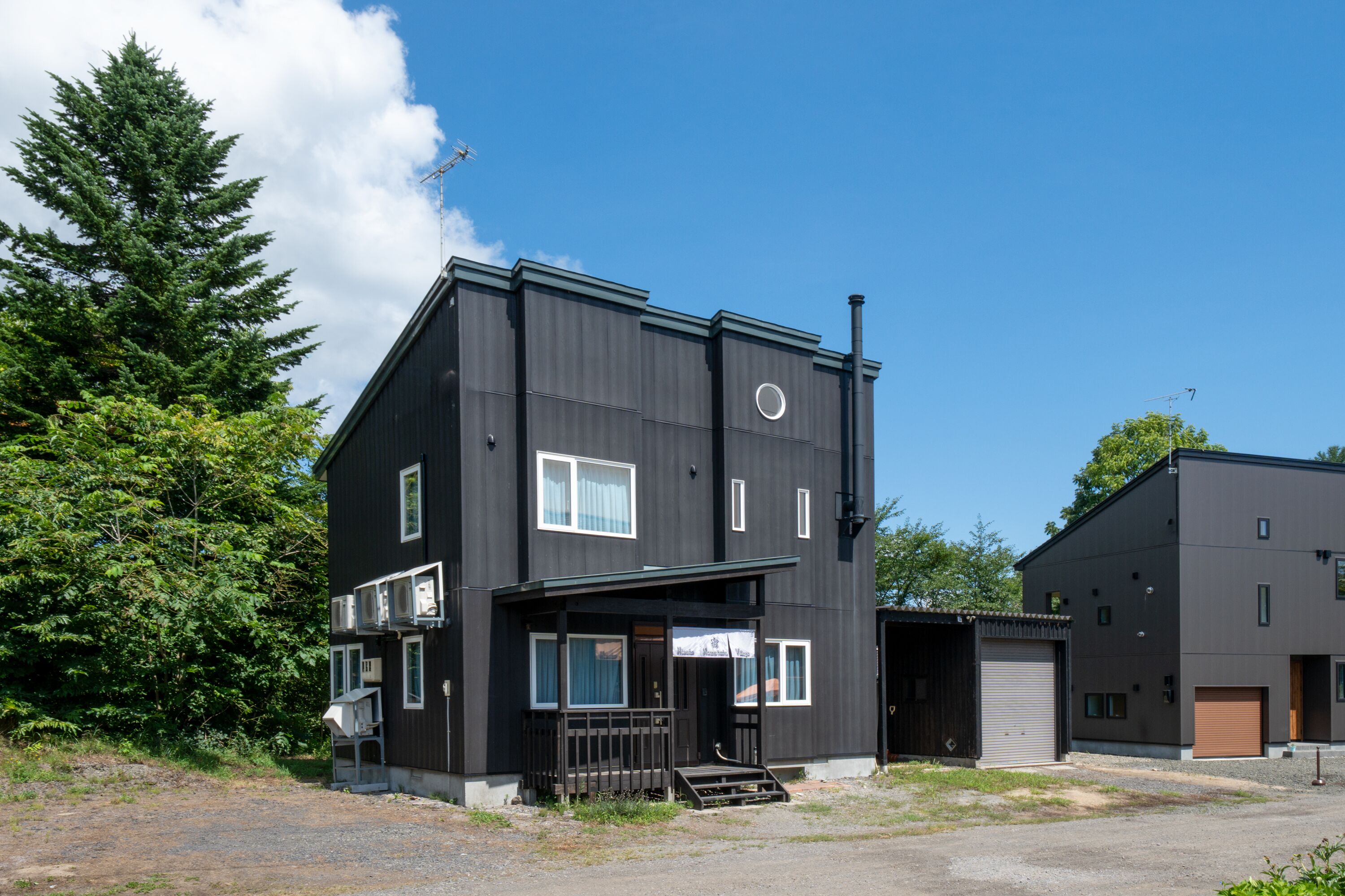 Un bâtiment moderne à deux étages, doté d’un toit plat, de grandes fenêtres et d’une cheminée bien visible.