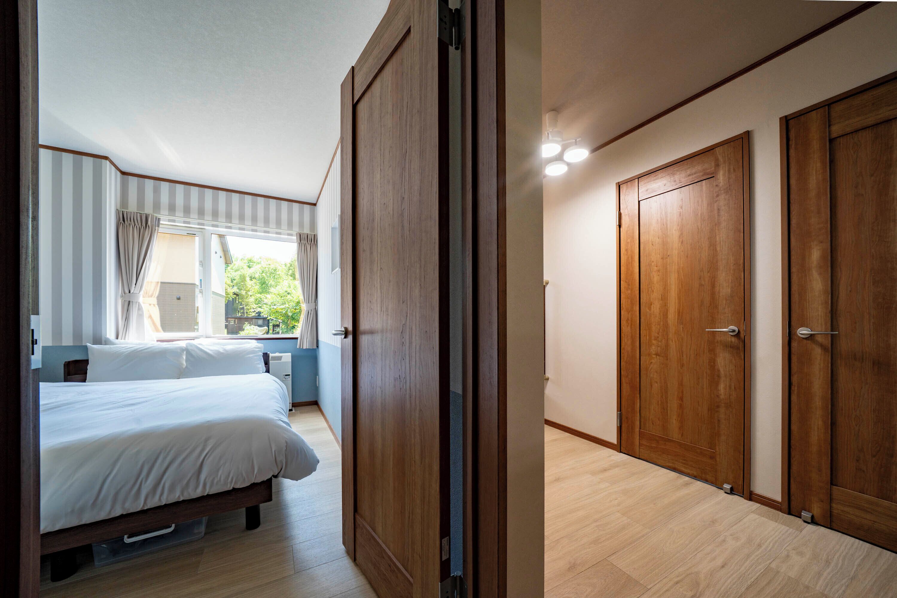 A bedroom with a bed, a window with curtains, and a wooden wardrobe.
