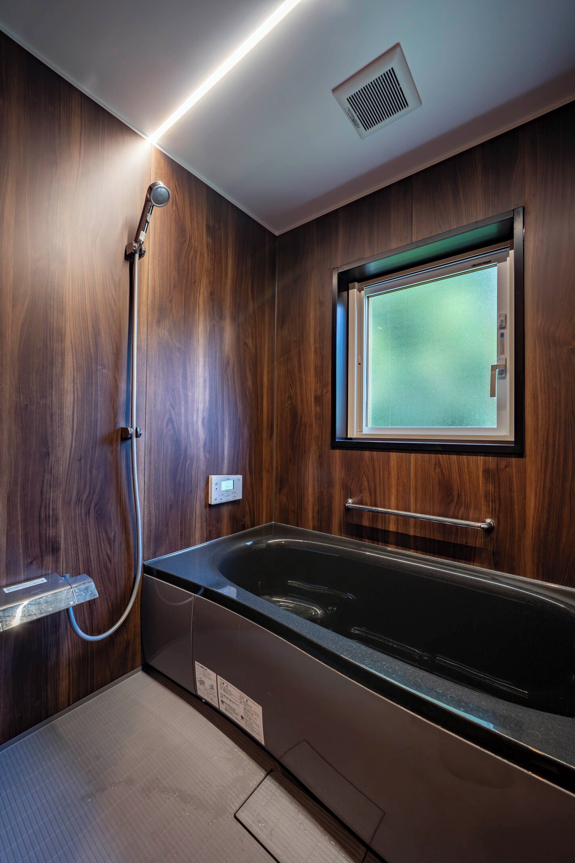 Un baño moderno con pared de madera, bañera integrada, ventana y ducha.
