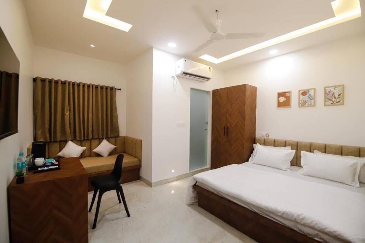 A hotel room with a bed, a desk, a chair, a wardrobe, and a ceiling fan.