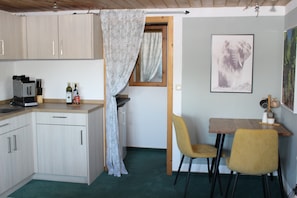 A kitchen with cabinets, a coffee machine, and a dining area with chairs and a table. - Studio Apartment with Shared Terrace and Wi-Fi (Bad Bayersoien)