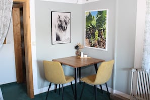 A room with a wooden table, two chairs, a radiator, and two framed pictures on the wall. - Studio Apartment with Shared Terrace and Wi-Fi (Bad Bayersoien)