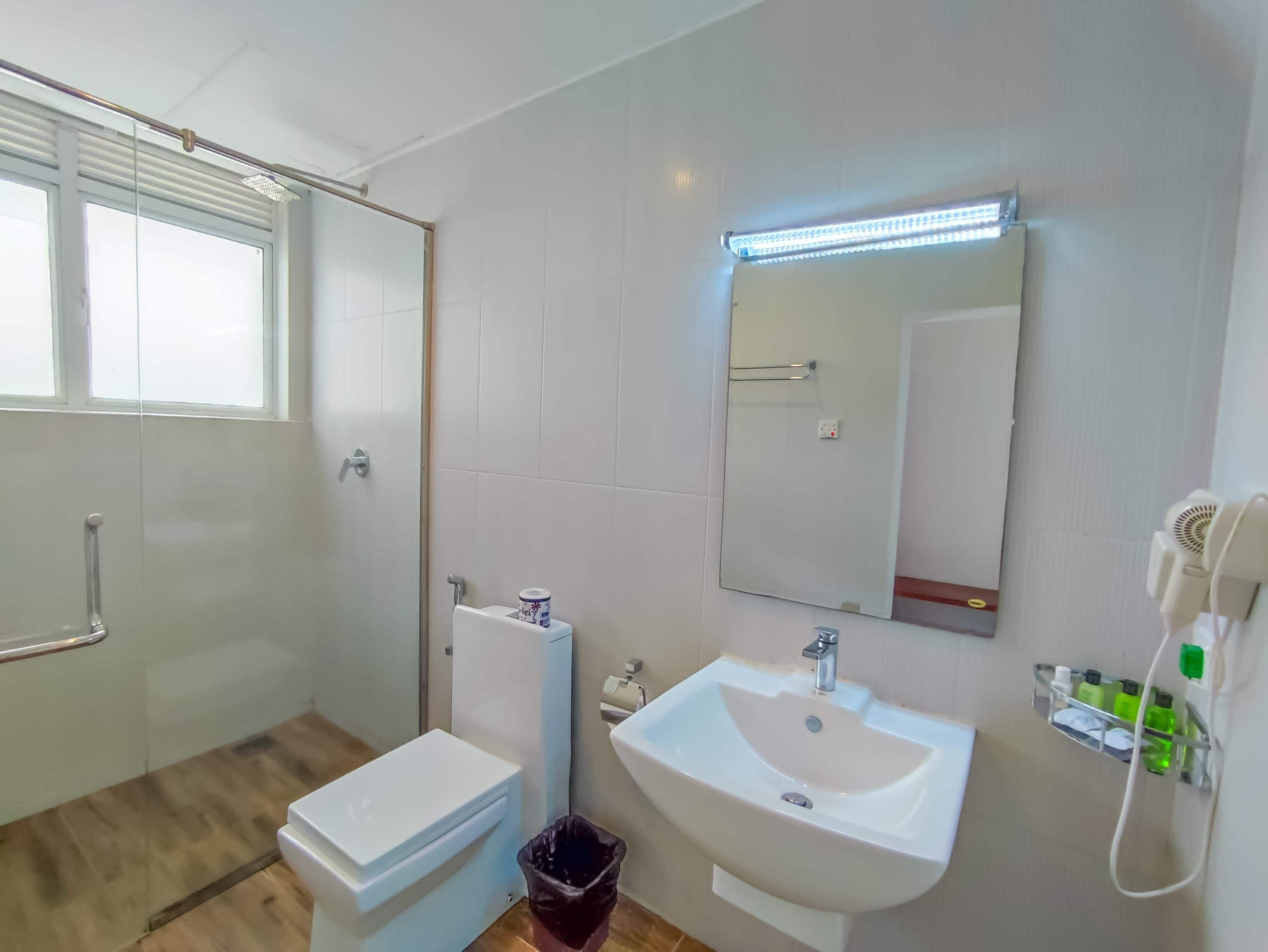 Een badkamer met toilet, wastafel en spiegel.