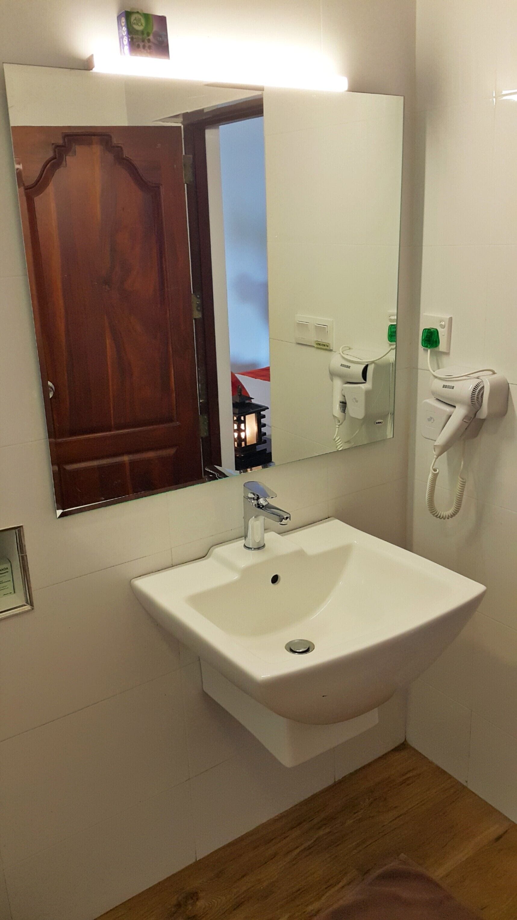 A bathroom with a white sink, a mirror, a hairdryer, and a telephone.