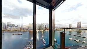 Un edificio de gran altura con vistas a un puerto deportivo y al horizonte de la ciudad.