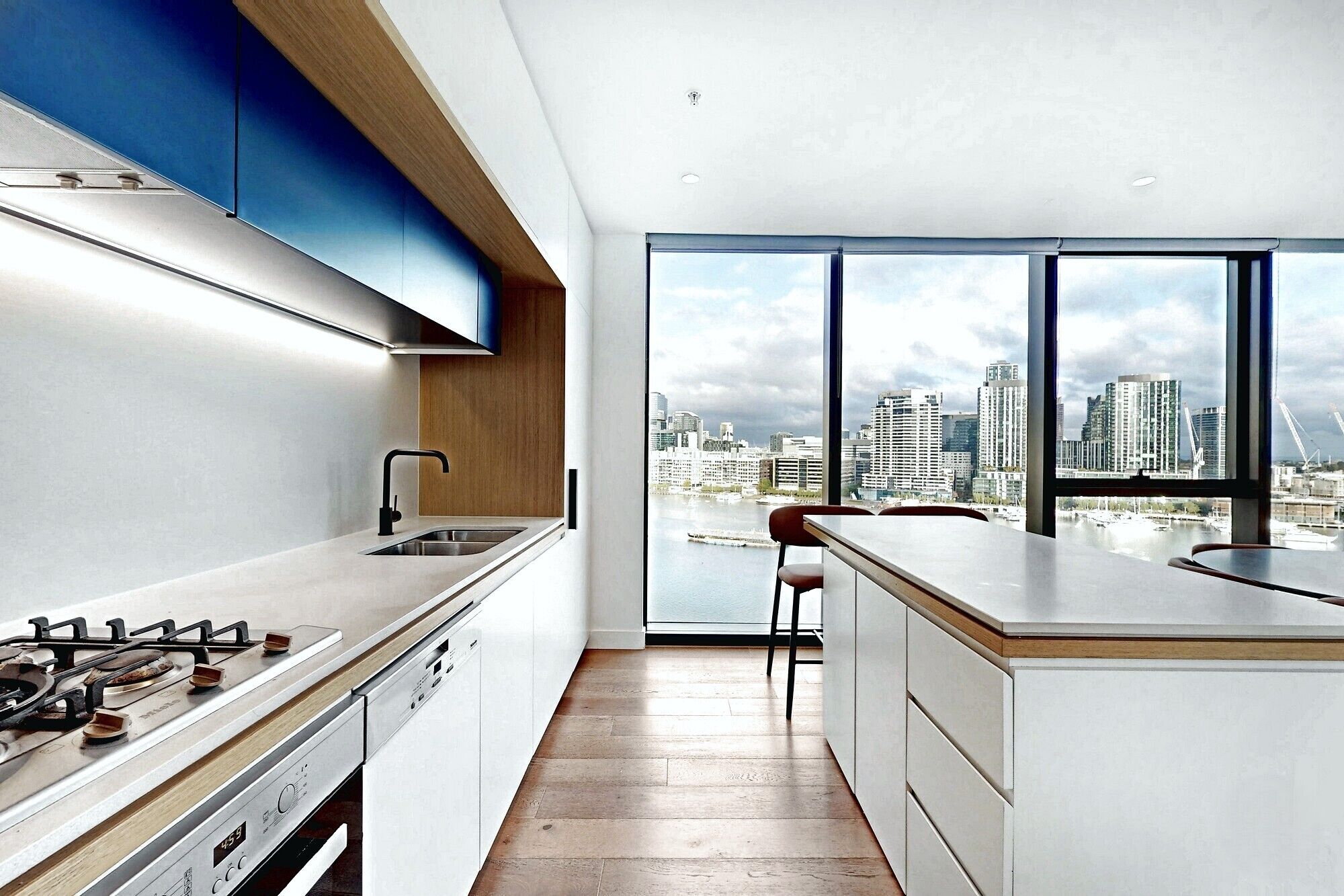 Eine moderne Küche mit Blick auf die Stadt, inklusive Gaskochfeld und großem Fenster.