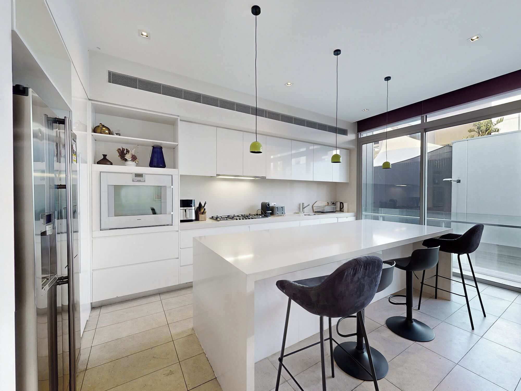 Una cocina moderna con armarios blancos, una isla central y taburetes de bar.