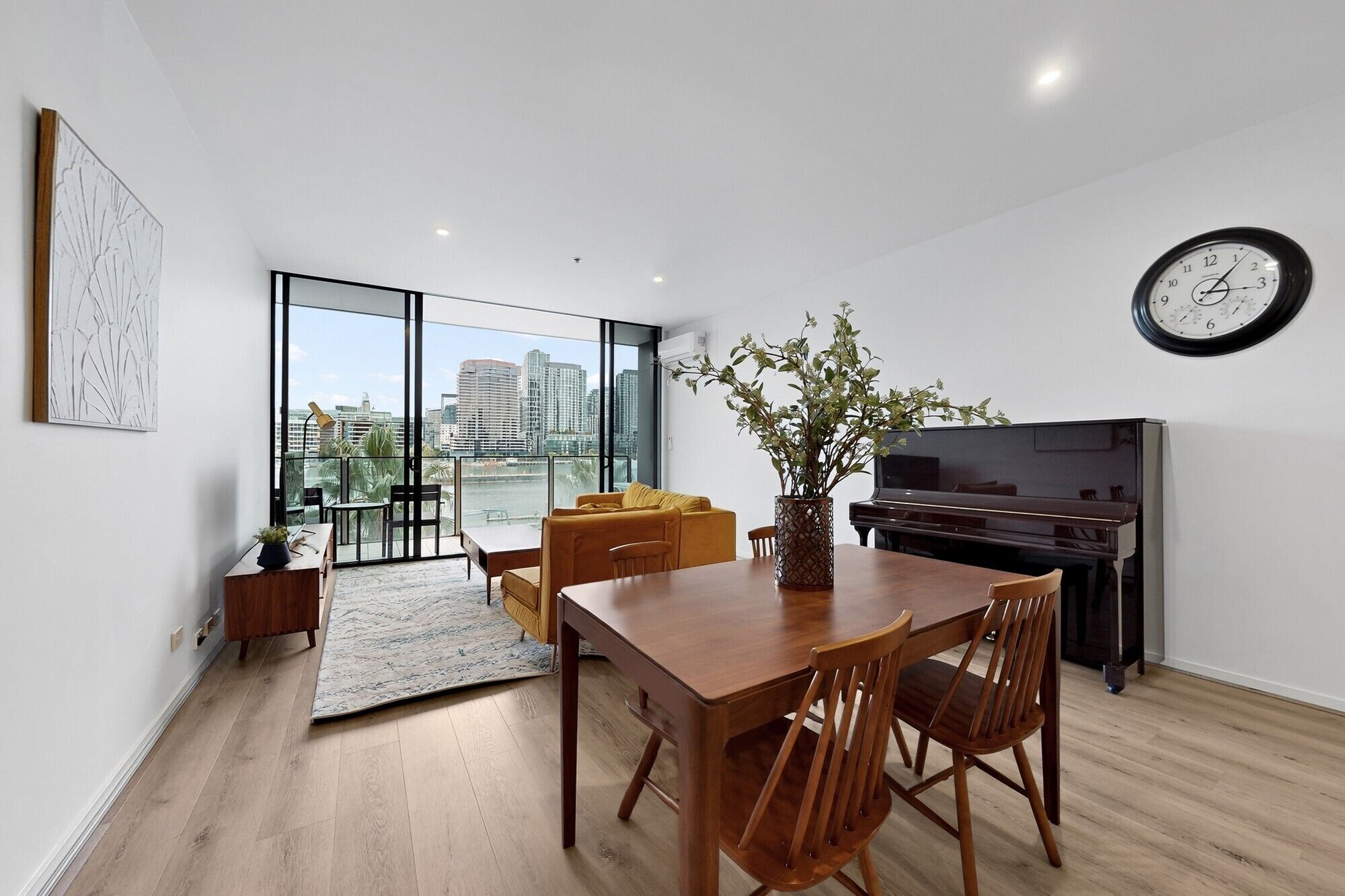Ein modernes Wohnzimmer mit Essbereich, einem Klavier und einem großen Fenster mit Blick auf die Stadt.