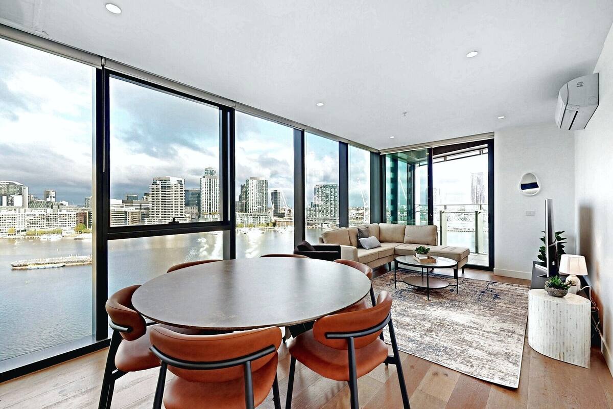 A modern living room with a large window overlooking a cityscape and water.