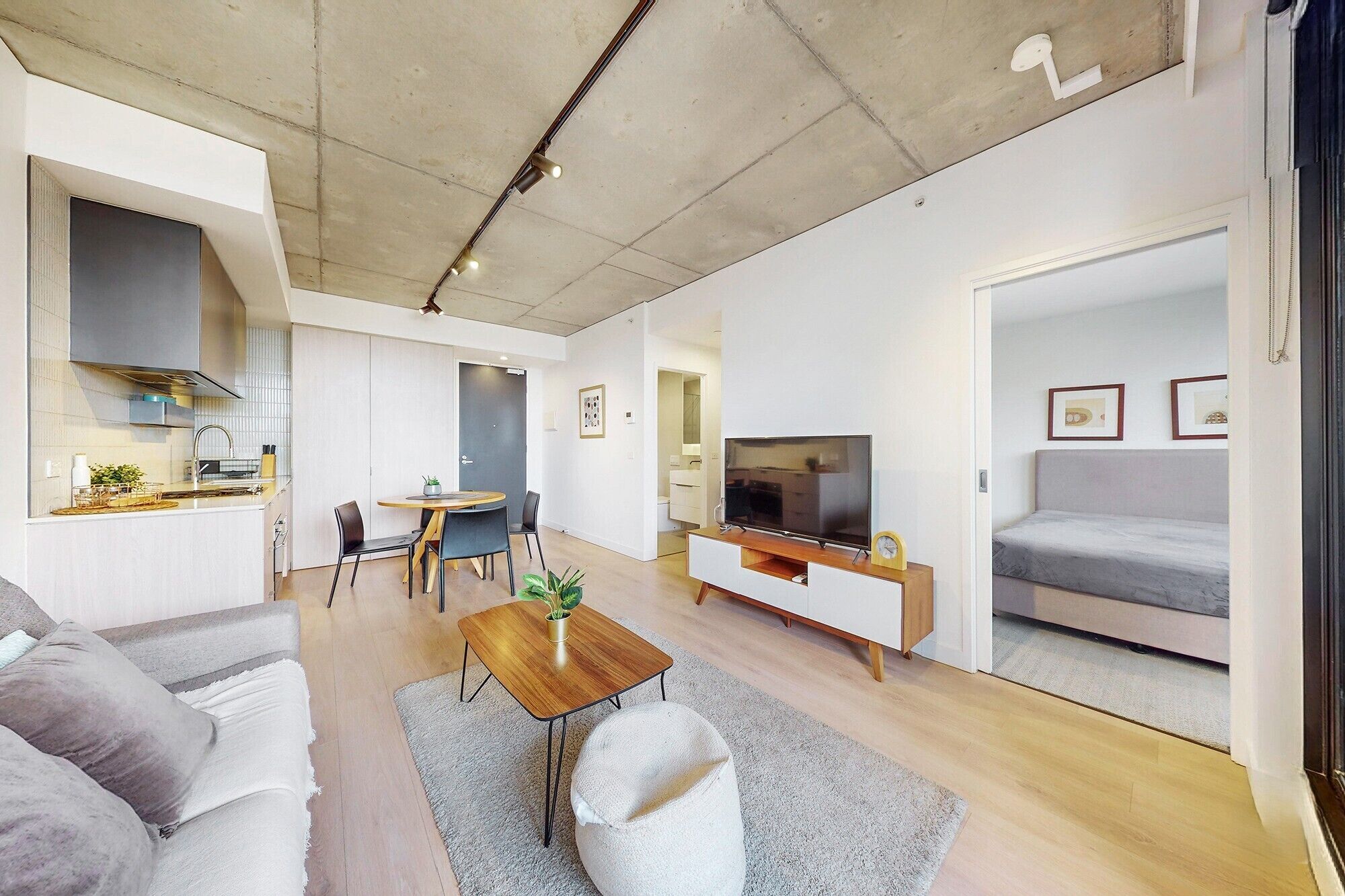 A modern apartment with a kitchen, dining area, living room, and a bedroom.