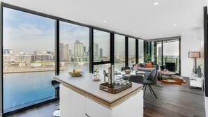 Un apartamento moderno con un ventanal grande que ofrece vistas a un paisaje urbano y al agua.