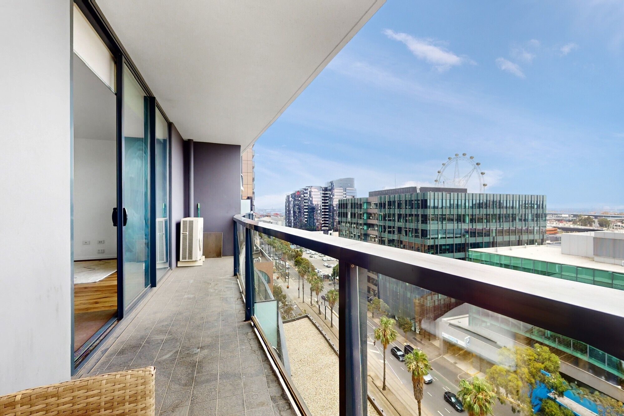 Ein Balkon mit Blick auf die Stadt, darunter moderne Gebäude und ein Riesenrad.