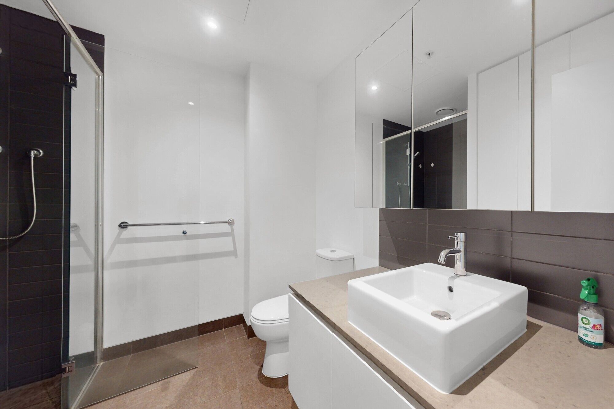 A modern bathroom with a shower, toilet, and sink.