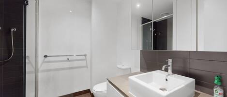 A modern bathroom with a shower, toilet, and sink.