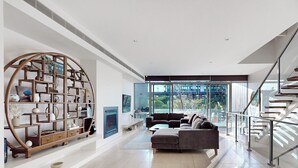 Una sala de estar moderna con chimenea, una amplia estantería, un sofá y una escalera.
