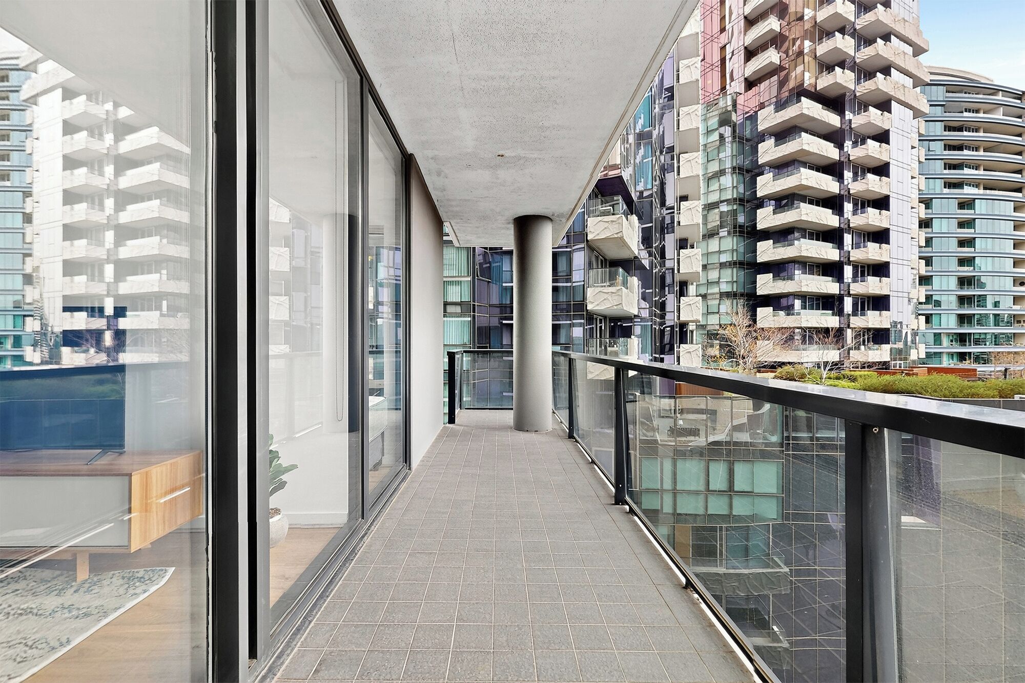 Un immeuble d’appartements moderne doté d’un balcon en verre, de grandes fenêtres et d’un plancher carrelé.