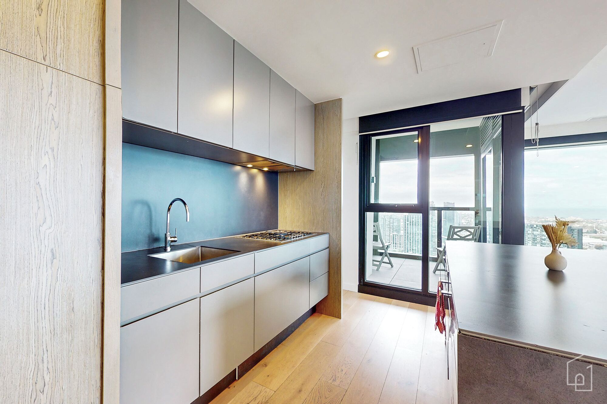 A modern kitchen with a stainless steel sink, a gas stove, and wooden cabinets.