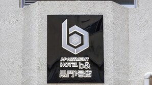 An entrance to an apartment hotel with a sign indicating it is the first high-rise in the area. - b&Kuromon (Osaka)
