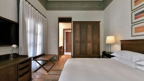 Una camera d'albergo con un letto, una scrivania, una televisione, un armadio e una lampada.