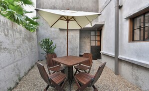 A patio with a table and chairs, a large umbrella, and a cactus plant. - LeeManorHotel (Xiamen)