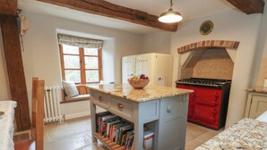 Une cuisine dotée d’un plan de travail en granit, d’une cuisinière rouge et d’une fenêtre donnant sur les arbres.