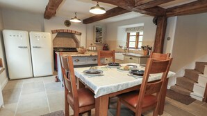 Una cucina accogliente con travi in legno, un tavolo da pranzo apparecchiato per quattro persone e un forno a scomparsa.