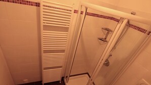 A shower area with a glass door, a white radiator, and tiled walls. - Quiet cozy apartment overlooking the lake, closed parking lot and pool, (Malcesine)
