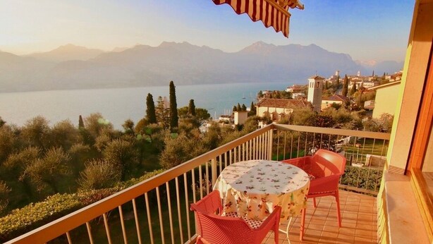A balcony with a table and chairs overlooking a lake and mountains. - Quiet cozy apartment overlooking the lake, closed parking lot and pool, (Malcesine)