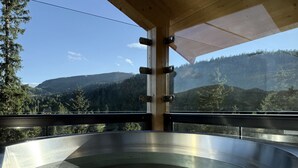Un bain à remous avec une terrasse en bois et une vue sur un paysage montagneux.