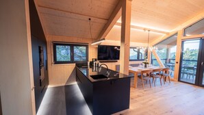 Een moderne keuken met een zwart kookeiland, houten balken en grote ramen.