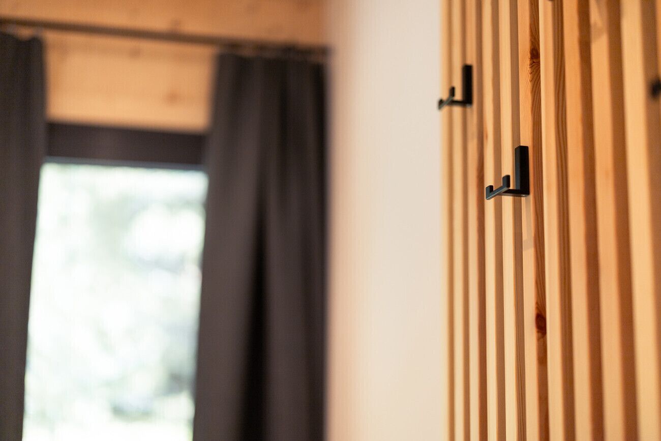 A room with a wooden slat wall, a window with curtains, and a door with a black handle.