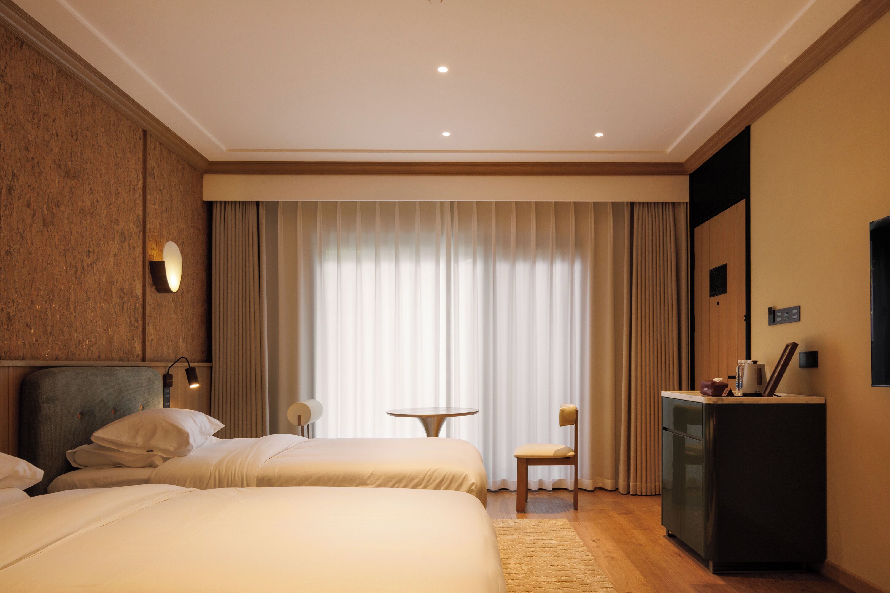 Ein Hotelzimmer mit zwei Betten, einem Schreibtisch, einem Stuhl und einem Fernseher.