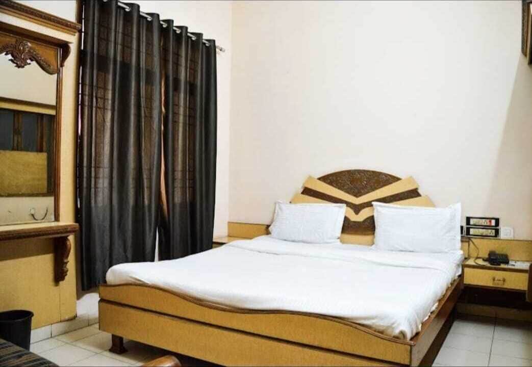 Habitación de hotel ordenada con cama, mesita de noche y un reloj de pared.
