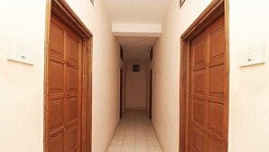 A corridor with wooden doors and tiled flooring. - Hotel Saiom Palace (Raipur)