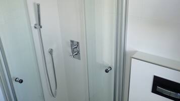 A modern bathroom with a glass-enclosed shower, a toilet, and a sink.
