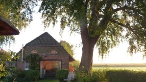 Una casa in mattoni con tetto spiovente, un portone d'ingresso e una panchina di fronte.