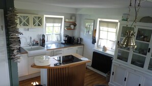 Una cucina con isola centrale, mobili bianchi, un termosifone e una lampada a sospensione.