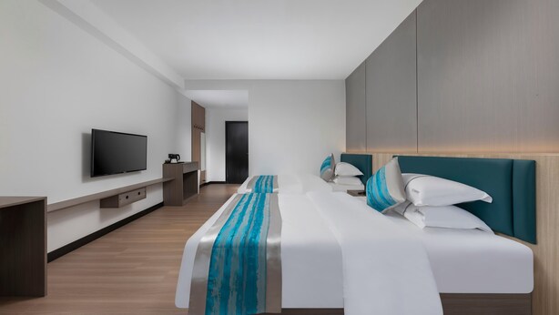 Ein modernes Hotelzimmer mit einem großen Bett, einem Flachbildfernseher und Holzboden.