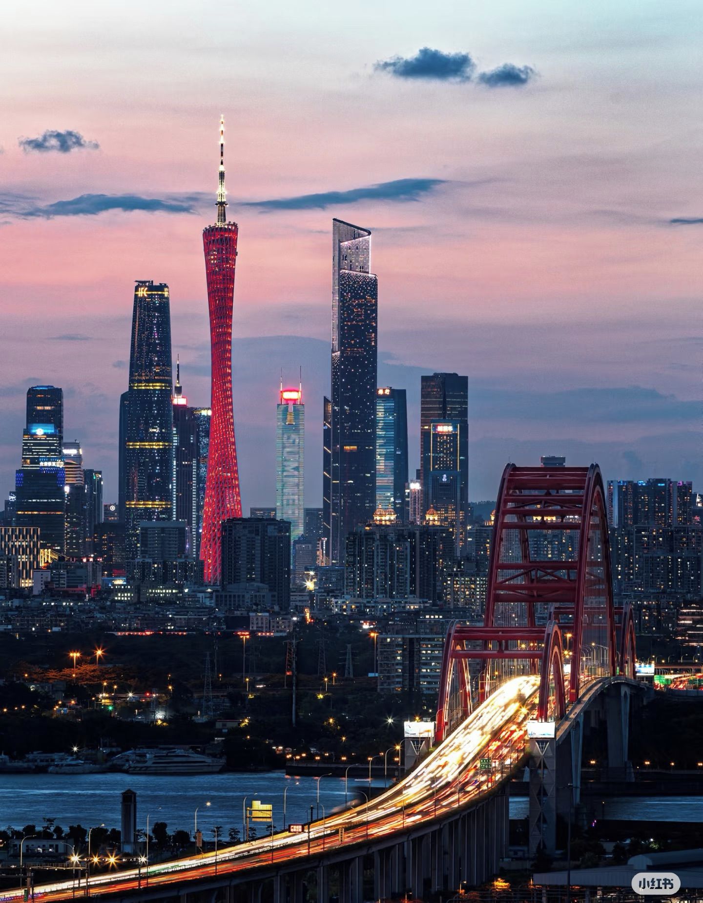A cityscape at dusk with a prominent tower and modern skyscrapers.