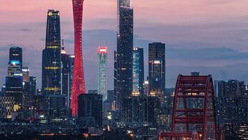 A cityscape at dusk with a prominent tower and modern skyscrapers.